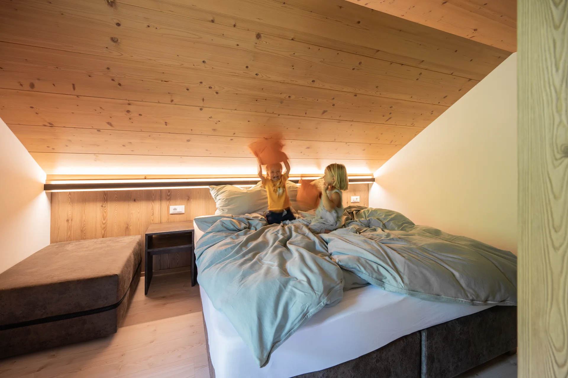 Kinder springen vergnügt auf dem Bett
